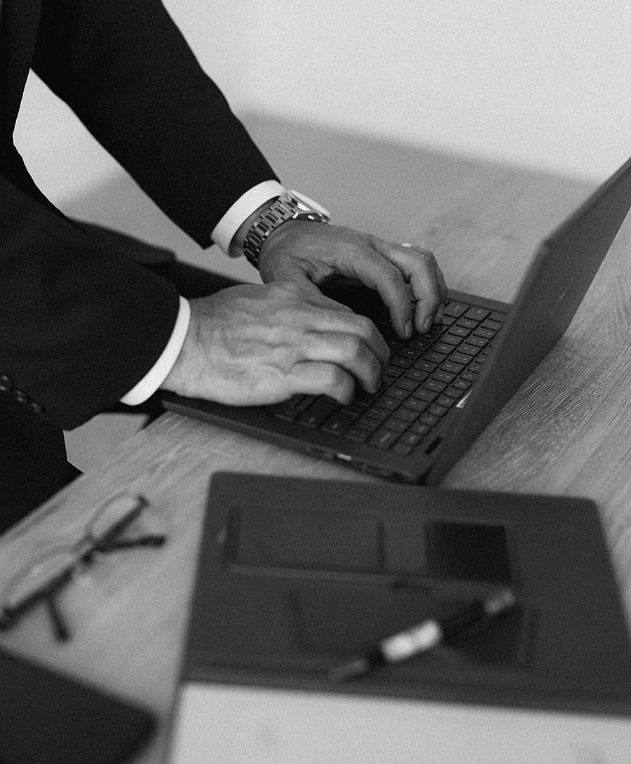Hands at work on a laptop beside a leather folio